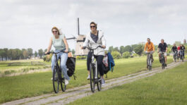 twee fietsers in de polder met een molen op de achtergrond