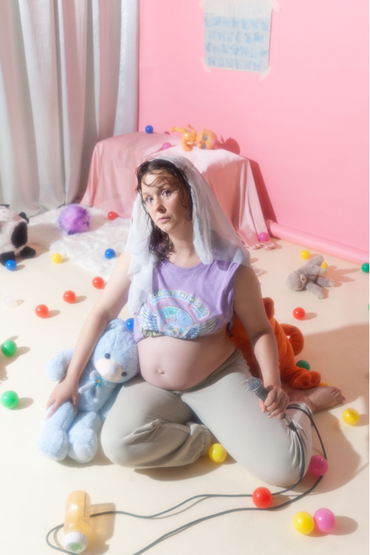 Campagnebeeld Kaatje Kooij’s Stand-Up Show: De Musical met zwangere vrouw zittend in kinderkamer
