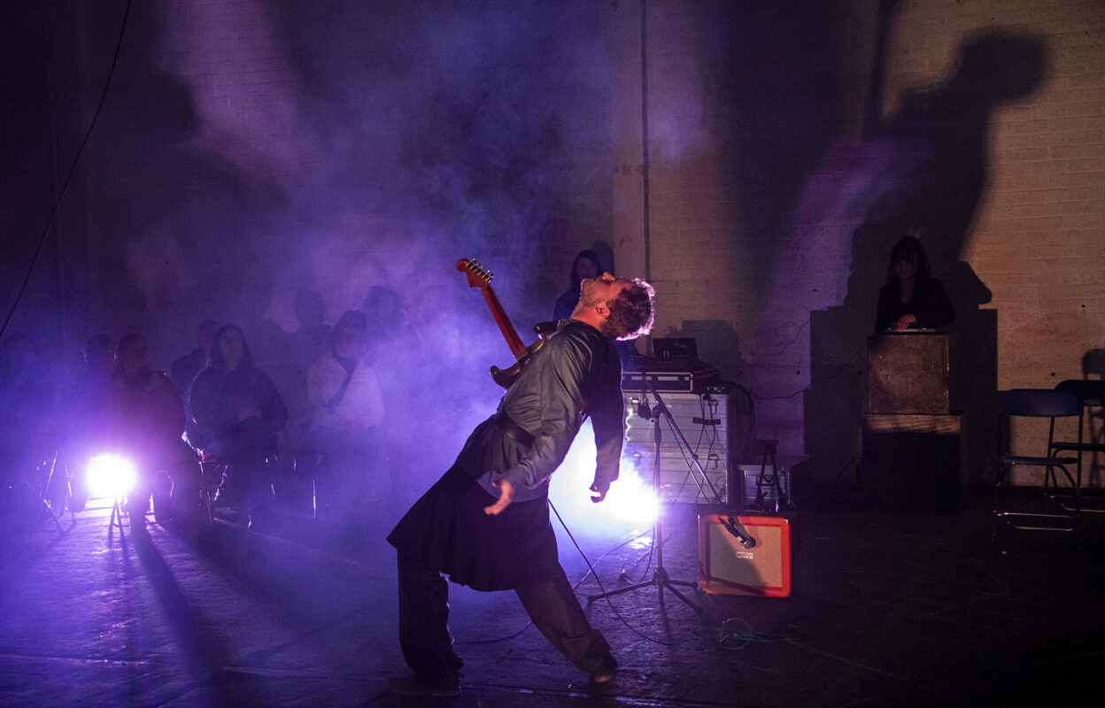 Gitarist met wijde armen in de spotlights ArtEZ Muziektheater