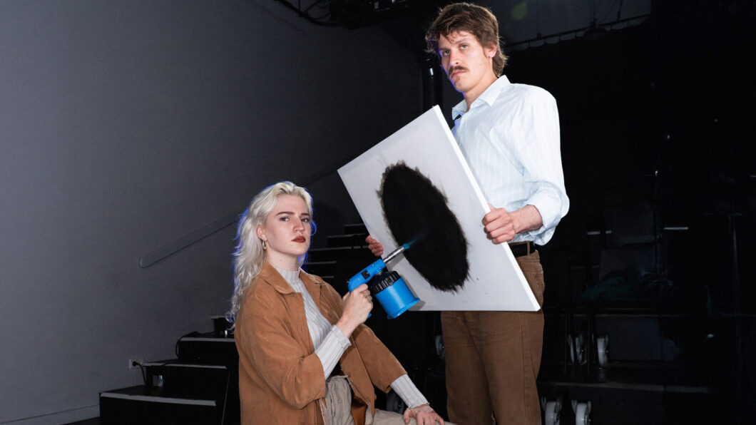 vrouw maakt met een brander een zwarte cirkel op een canvas, vastgehouden door een man, campagnebeeld voor voorstelling NUL