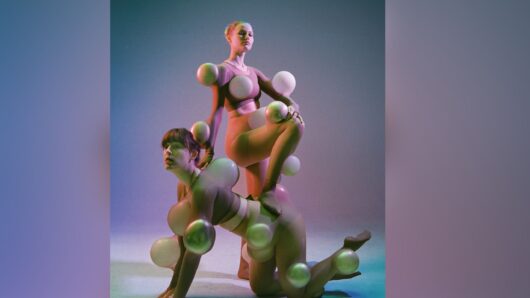 Twee performers poseren in een studio met zachte paarse en groene belichting. Ze dragen huidkleurige kostuums met ronde, bolvormige objecten die op verschillende plekken aan hun lichaam zijn bevestigd, waardoor hun silhouetten vervormd en overdreven worden. Eén performer knielt op handen en knieën terwijl de ander met één voet op haar rug staat. De afbeelding speelt met vormen, lichaamsbeelden en sculpturale poses. Campagnebeeld van Pretty Privilege