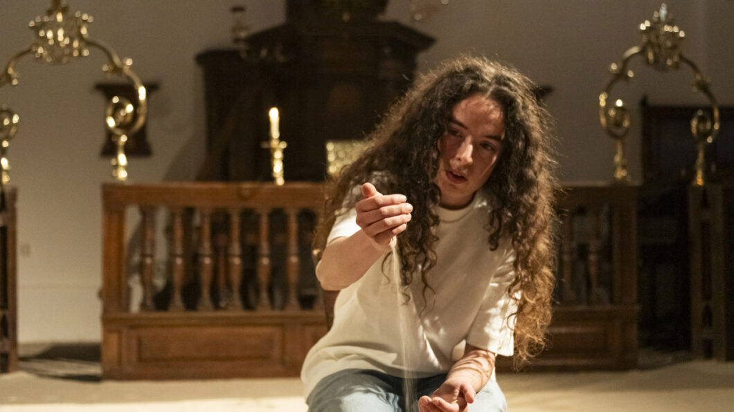 Anna an Sich - vrouw in een kerkje die zand door haar handen laat glijden