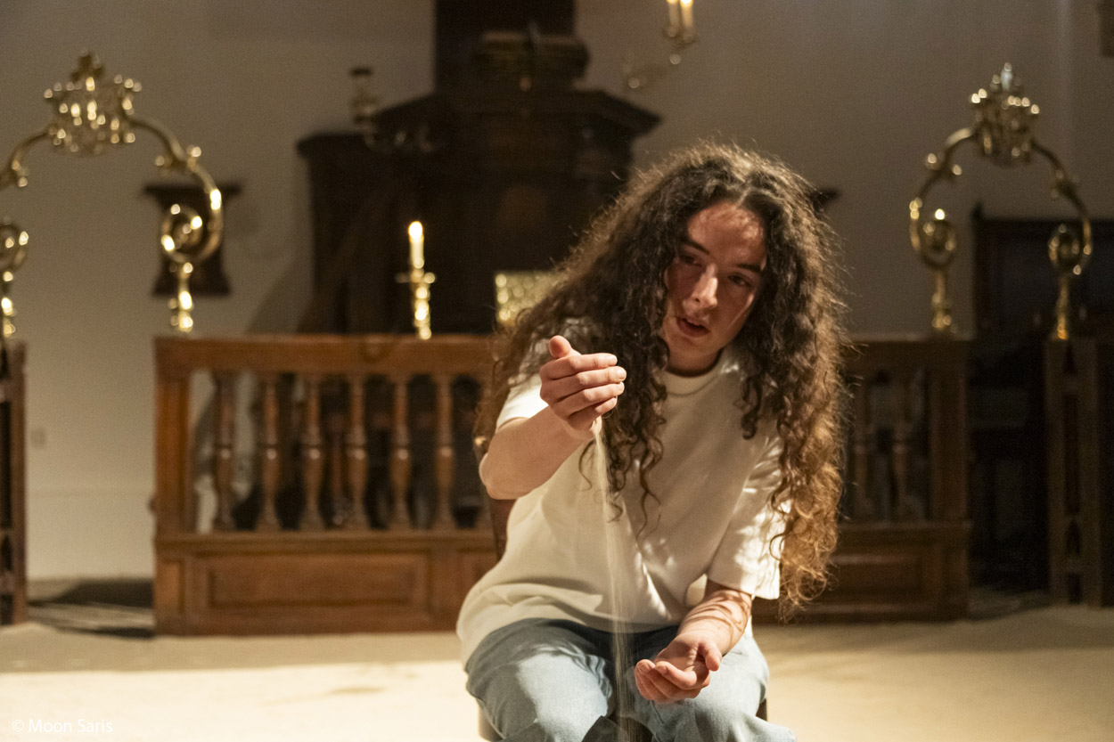 Anna an Sich - vrouw in een kerkje die zand door haar handen laat glijden