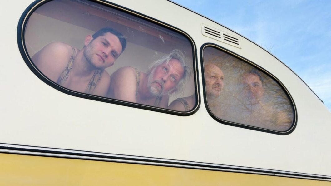 WAAN van BOT - 4 mannen in hemd achter het raam van een kleine caravan
